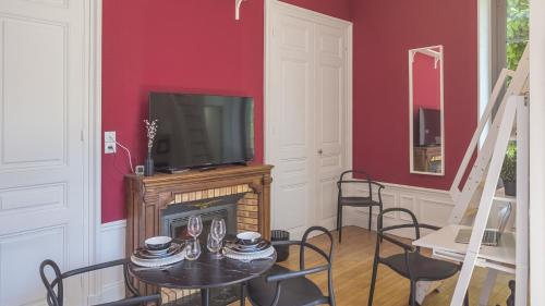 a living room with a television and a table with chairs at BonAppart 2 - Charme Napoléonien & Confort in Troyes