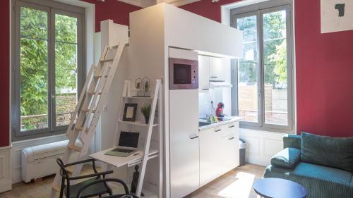 a room with a white refrigerator and a desk with a laptop at BonAppart 2 - Charme Napoléonien & Confort in Troyes
