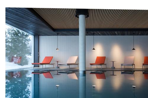 a group of chairs sitting in a room with a pool at ICARO Hotel in Alpe di Siusi