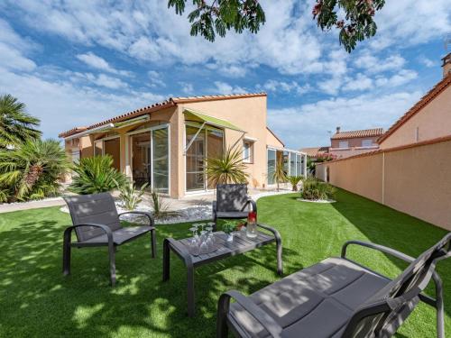 un prato con sedie e un tavolo con bicchieri di vino sopra di Villa Ladine by Interhome a Le Barcarès