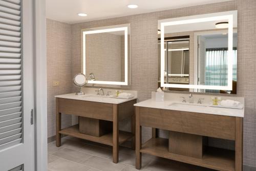 two sinks in a bathroom with two mirrors at Hilton Fairfax, Va in Fairfax