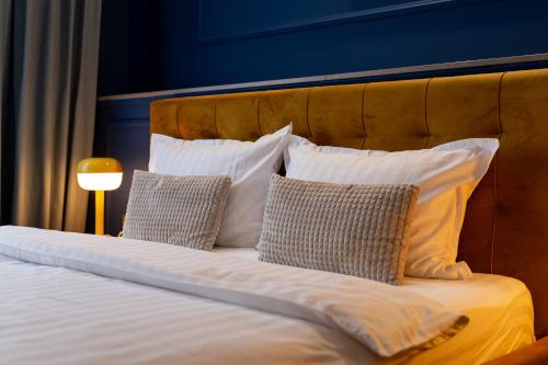 a bed with white pillows and a blue wall at Hotel Cocó in Timişoara