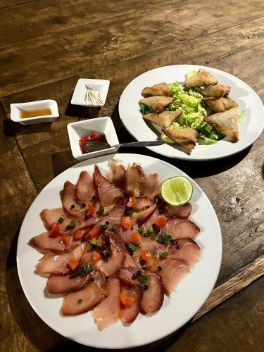 two plates of food on a wooden table at Hôtel La Terrasse du Voyageur in Antsiranana