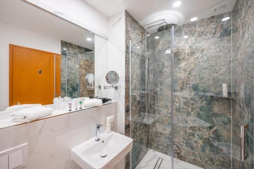 ein Badezimmer mit Waschbecken und Glasdusche in der Unterkunft Arkona Strandhotel in Binz