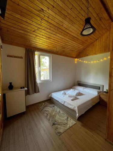a bedroom with a large bed and a wooden ceiling at Casuta din livada in Turda