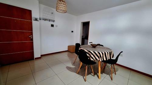 a dining room with a table and two black chairs at Departamento Cofico in Cordoba
