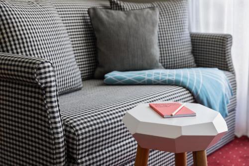 a living room with a couch and a table with a book at ICARO Hotel in Alpe di Siusi
