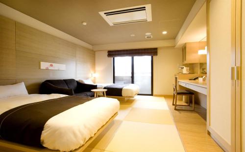 a hotel room with a bed and a living room at Hana Beppu in Beppu