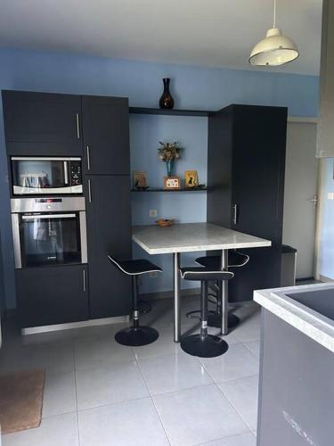 - une cuisine avec une table et deux tabourets dans l'établissement Maison girondine près de saint emilion, à Saint-Magne-de-Castillon