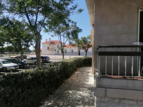 a building with cars parked in a parking lot at Casa da Estação in Sines