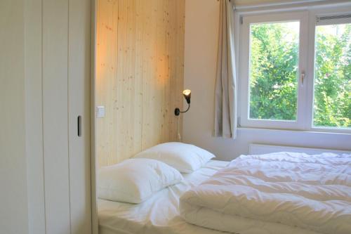 a bed with two pillows in a bedroom with a window at Previnaireweg 19 in Callantsoog