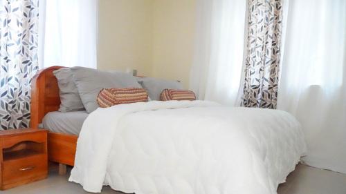 a bedroom with a white bed and a chair at Kara Apartments in Bortianor