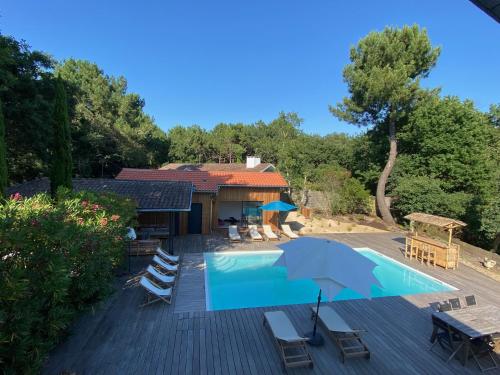 une piscine avec des chaises et un parasol à côté d'une maison dans l'établissement Villa Sand Golf by Carlon Luxury Rentals, à Seignosse