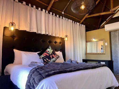 a bedroom with a large bed with white sheets at Lapa Lange Game Lodge in Mariental