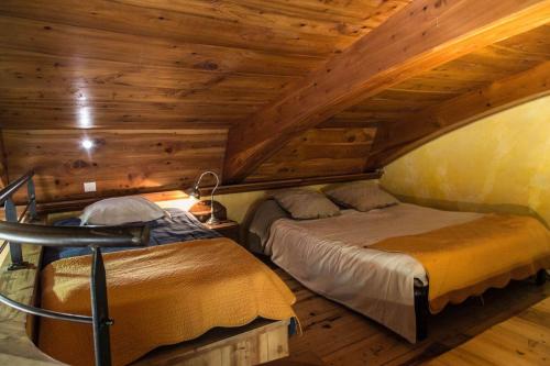 deux lits dans une chambre avec plafonds en bois dans l'établissement Hébergement insolite en pleine nature & piscine 2 à 11 p - Gites Les Princes à LANAS, à Lanas