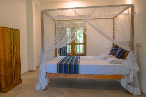 a bedroom with a canopy bed and a window at Cinnamon Lagoon Villas in Unawatuna
