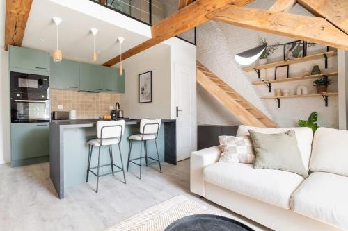 un salon avec un canapé blanc et une cuisine dans l'établissement L'élégant - Appartement Fonctionnel Plein-centre de Douai, à Douai