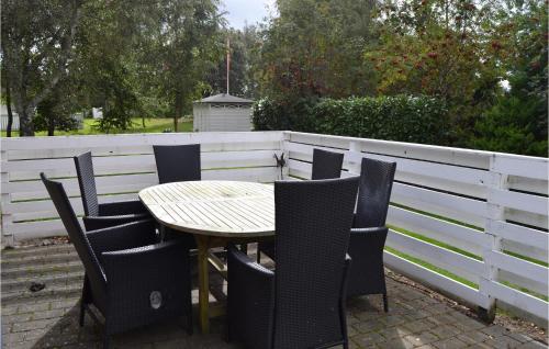 a wooden table and chairs and a white fence at Holiday Home Juelsminde With Fireplace 7 in Juelsminde