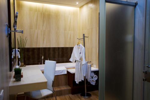 a bathroom with a sink and a shower with a robe at The Pinnacle Hotel and Suites in Davao City