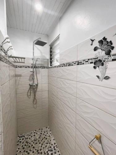 a white bathroom with a shower and a tiled floor at Villa Caraïbes in Sainte-Luce
