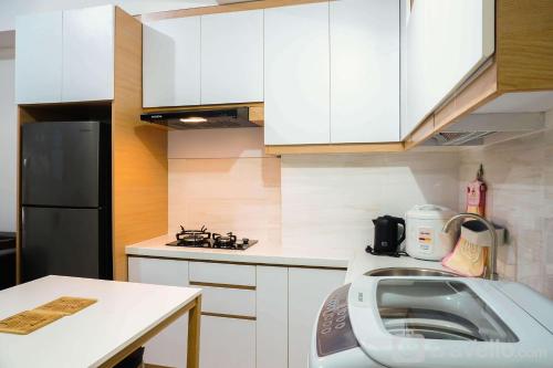 a kitchen with white cabinets and a black refrigerator at Highest Value 2BR Apartment at M-Town Residence By Travelio in Tangerang