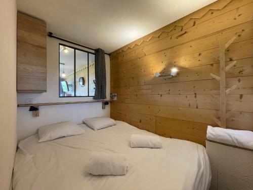 un lit dans une chambre avec un mur en bois dans l'établissement Homency - Résidence Le Commodore 223, à L'Alpe-d'Huez