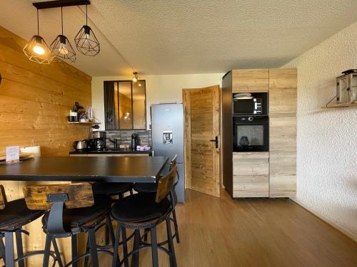 La cuisine est équipée d'un bar avec tabourets et d'un réfrigérateur. dans l'établissement Homency - Résidence Le Commodore 223, à L'Alpe-d'Huez