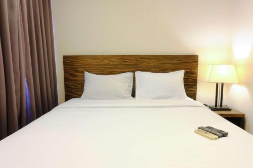 a bedroom with a white bed with a wooden headboard at Modern Look 3BR at Apartment Braga City Walk By Travelio in Bandung