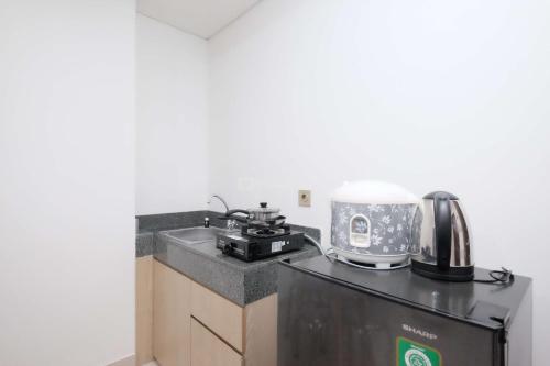 a kitchen with a sink and a coffee maker on a counter at New Furnished and Homey 2BR at Transpark Cibubur Apartment By Travelio in Depok
