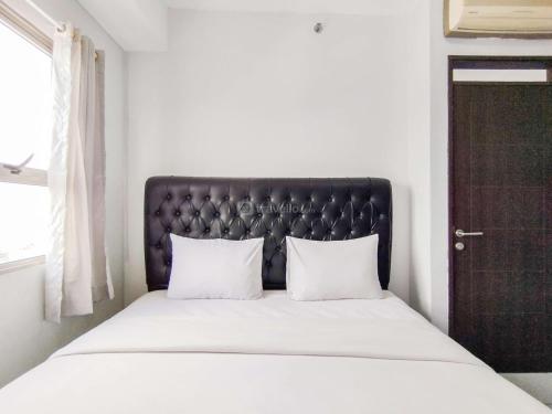 a bed with a black headboard and two white pillows at Spacious and Cozy 2BR Apartment Mekarwangi Square Cibaduyut By Travelio in Bandung