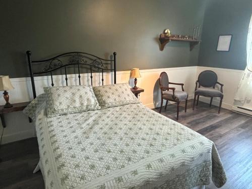 a bedroom with a bed and two chairs at Auberge Presbytere Mont Lac-Vert in Hébertville