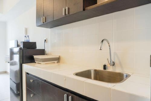 eine Küche mit Spüle und Kühlschrank in der Unterkunft Comfortable and Well Design Studio Tokyo Riverside PIK 2 Apartment By Travelio in Rawalembang