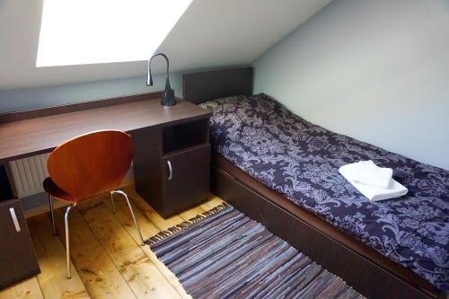 een slaapkamer met een bed, een bureau en een stoel bij PIZĀ Guest House & Campsite in Miķeļtornis