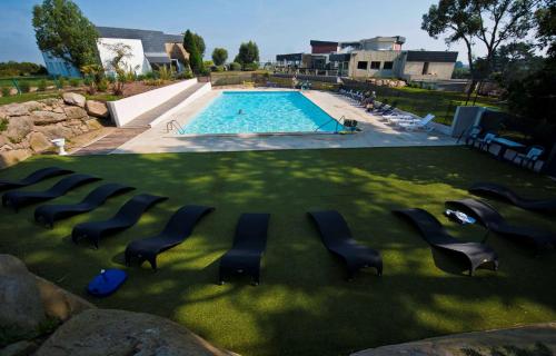 a group of chairs sitting in the grass near a swimming pool at Brit Hotel Golfhotel Saint Samson in Pleumeur-Bodou