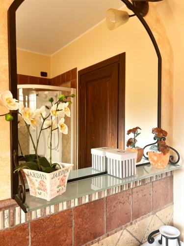 a bathroom counter with a mirror and flowers on it at Relaxing farmhouse in San Marino