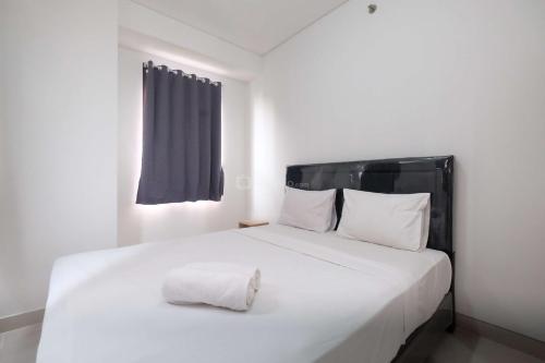 a bedroom with a white bed with a pillow on it at Fully Furnished and Cozy 2BR at Transpark Cibubur Apartment By Travelio in Depok