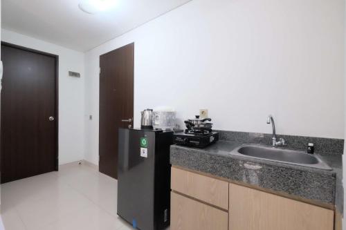 a kitchen with a sink and a counter top at Fully Furnished and Cozy 2BR at Transpark Cibubur Apartment By Travelio in Depok