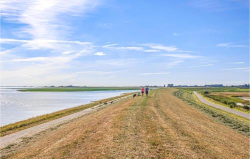 two people walking down a dirt road next to the water at Awesome Home In Heinkenszand With Wifi in Heinkensand