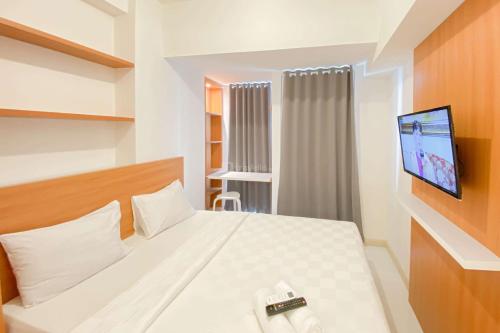 Un dormitorio con una cama con un televisor en la pared. en Pleasurable and Tidy Studio at Tokyo Riverside PIK 2 Apartment By Travelio, en Rawalembang