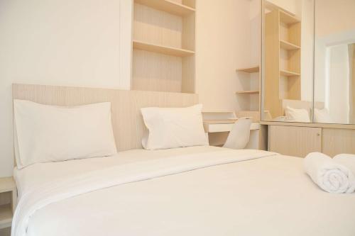 a white bed with white pillows and a mirror at Comfort and Relaxing 2BR (No Kitchen) Tokyo Riverside PIK 2 Apartment By Travelio in Rawalembang