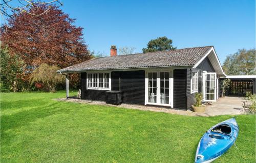 a small house with a blue boat in the yard at Lovely Home In Føllenslev With Wifi in Føllenslev