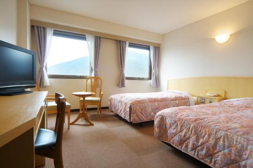 a hotel room with two beds and a flat screen tv at Hotel Sunshine Tokushima in Tokushima