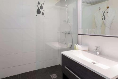 a white bathroom with a sink and a shower at Brit Hotel du Lac in Saint-Paul-lès-Dax