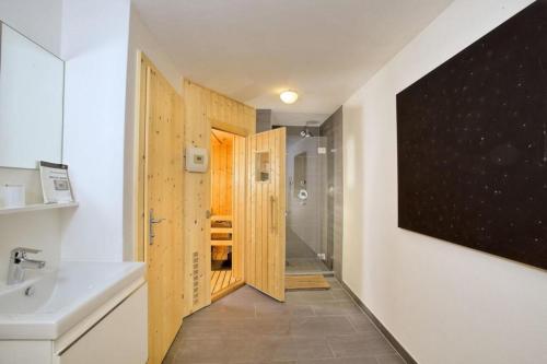 La salle de bains est pourvue d'une porte en bois et d'un lavabo. dans l'établissement Schöneben Chalet Ferienwelt, à Wald im Pinzgau