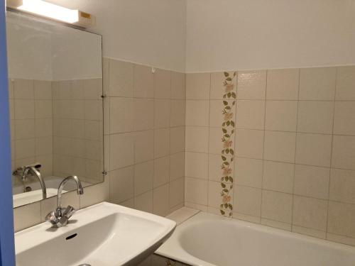 une salle de bain avec un lavabo, une baignoire et un miroir dans l'établissement La Perle Rose, à Saint-Jean-de-Monts