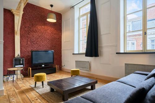 a living room with a couch and a tv at Old Lille charming duplex apartment in Lille
