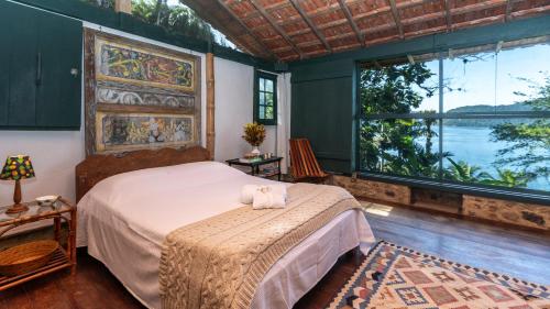 a bedroom with a bed and a large window at Angra House - Linda Casa em ILHA in Angra dos Reis