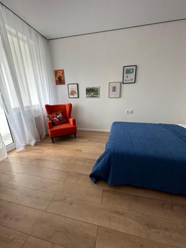 a bedroom with a blue bed and a red chair at Cozy Urban Retreat in Prigorodnyy