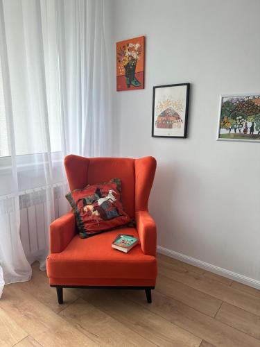 an orange chair with a pillow in a room at Cozy Urban Retreat in Prigorodnyy