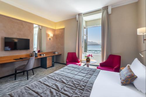 a hotel room with a bed and a desk and a window at Impérial Palace in Annecy